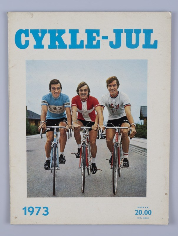 Drei Menschen auf Fahrrädern auf einer Straße mit Häusern, Bäumen und einem klaren blauen Himmel, mit Text "Cykle-Jul 1973 - Cyclocross Magazine" oben und unten.