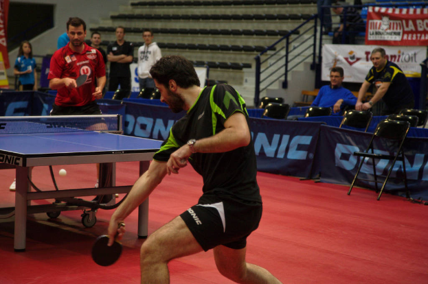 Eine Gruppe von Menschen in verschiedenen Farben, darunter schwarz, wei├č und blau, versammelte sich um einen Tisch mit einem Spiel, St├╝hlen und einer Treppe im Hintergrund.