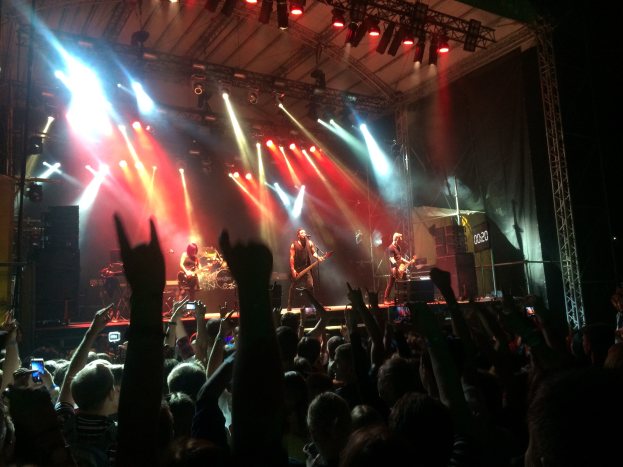 Eine Gruppe von Menschen, die auf einer hell erleuchteten Bühne spielt, einige spielen Instrumente, während andere das Ereignis mit ihren Handys aufzeichnen.