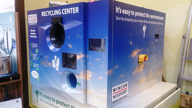 Blaues Recycling-Zentrum mit einem "Recycling-Zentrum"-Schild in der Mitte, einem Gestell mit Gegenständen links, einem einzelnen Gegenstand auf dem Boden rechts und Hintergrundbeleuchtung und Wand.