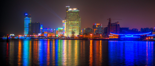 Ein Wasserlauf am Boden, mit Gebäuden und Pfählen in der Mitte des Bildes.