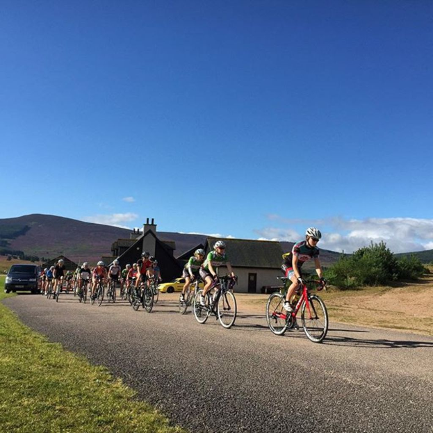 Eine Gruppe von Menschen, die mit dem Himmel im Hintergrund Fahrrad fährt.