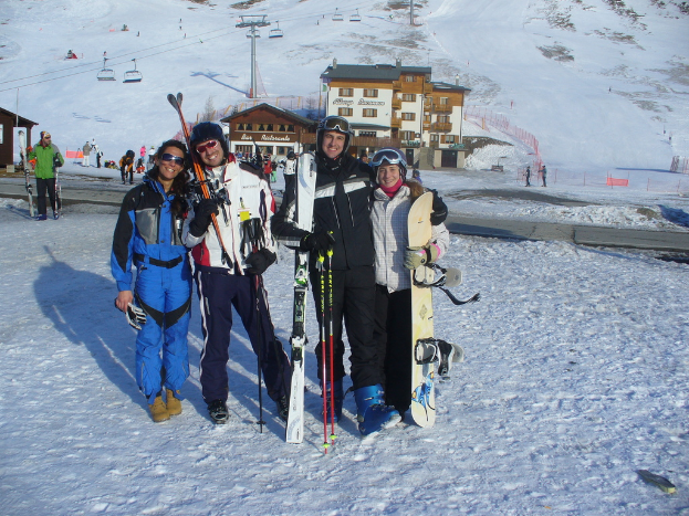 Vier Personen posieren mit Skaterpads und Werkzeugen vor einer schneebedeckten Berglandschaft.