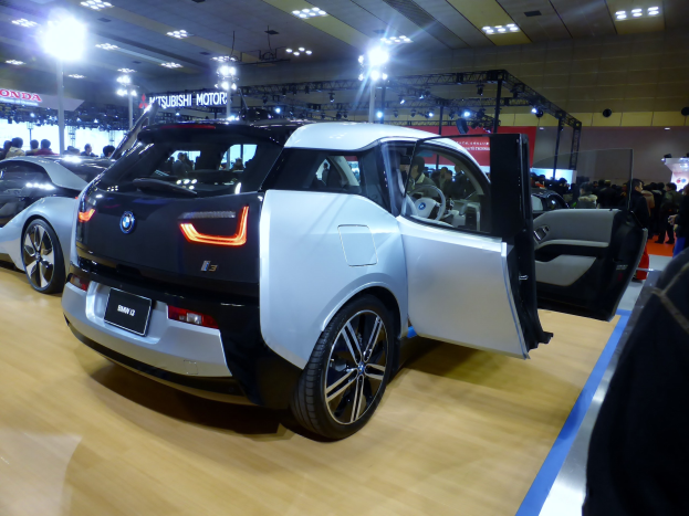 Weißer und schwarzer BMW i3 Elektroauto auf der Internationalen Automobil-Ausstellung in Frankfurt, umgeben von Menschen, mit beleuchteter Decke und Informationsschildern im Hintergrund.