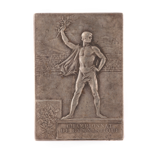 Eine silberne Plakette mit einer Statue eines triumphierenden Mannes, der einen Lorbeerkranz hält, mit der Inschrift "Championnat de Gymnastique."