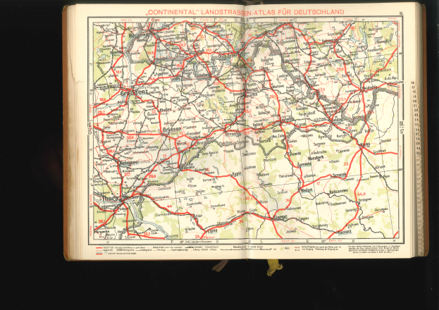 Ein aufgeschlagenes Buch, das eine detaillierte Deutschlandkarte mit Straßen und Autobahnen zeigt, vor schwarzem Hintergrund.