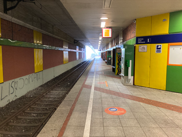 Ein Bahnhof in Berlin, Deutschland, mit einem Zug auf den Schienen, beleuchtet von Deckenlampen, Graffiti an der linken Wand und ein paar Gegenständen auf der rechten Seite.