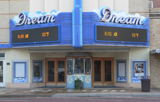 Außenansicht des Dream Theaters in St. Louis, Missouri, mit Glastüren und Fenstern, einem Namensschild, einem Müllcontainer, einem Topf mit einer Pflanze und einer Straße am Boden.
