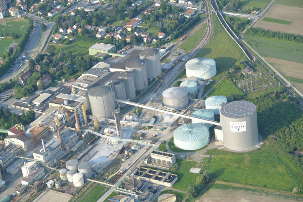 Luftaufnahme eines Vororts mit zahlreichen Gebäuden, Häusern, Bäumen und Fahrzeugen auf der Straße.