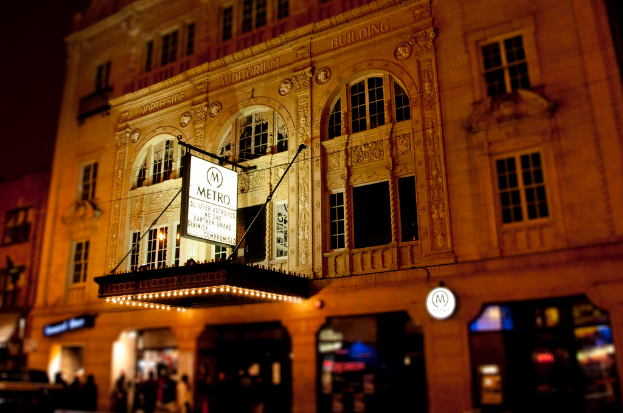 Ein gelbes Gebäude mit Geschäften und einer weißen Tafel mit der Aufschrift "Metro" an der vorderen Unterseite.