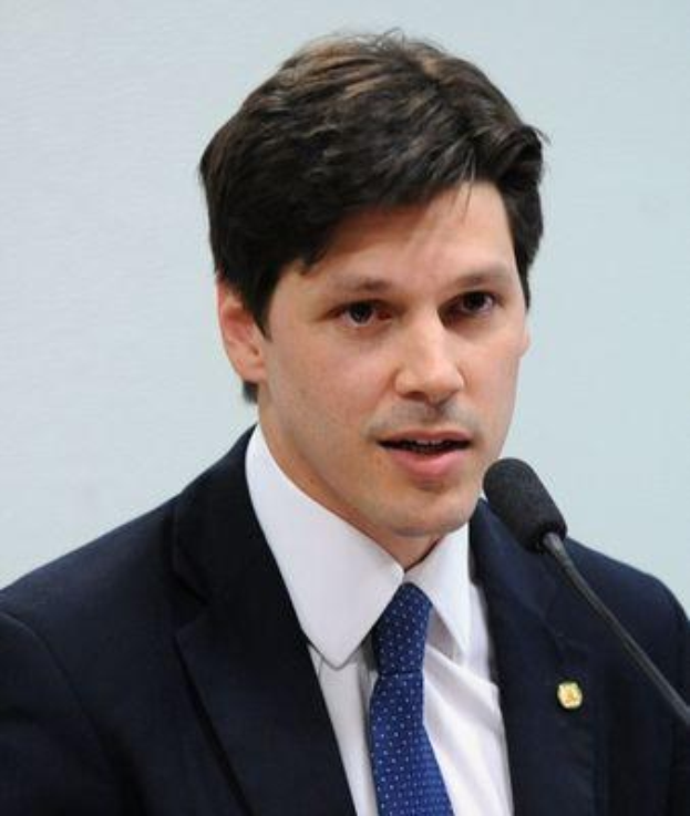 Mann im Anzug und Krawatte spricht in ein Mikrofon an einem Podium, wahrscheinlich zur Genehmigung eines Gesetzes durch die Regierung.