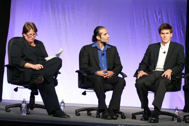 Drei Männer sitzen auf Stühlen mit ein paar Flaschen daneben.