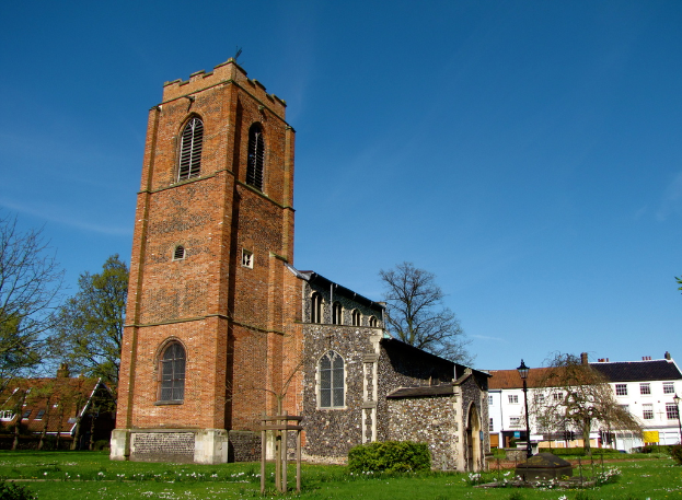 Eine grüne Fläche mit einem Pfahl, Gebäuden und Bäumen im Hintergrund.