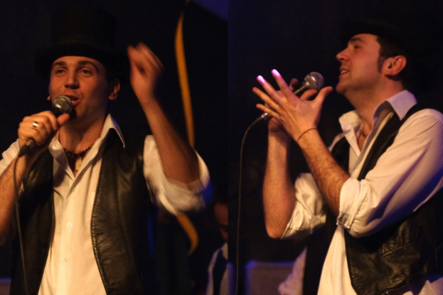 Eine Gruppe von Menschen mit zwei Individuen, die im Vordergrund in Mikrofone singen.