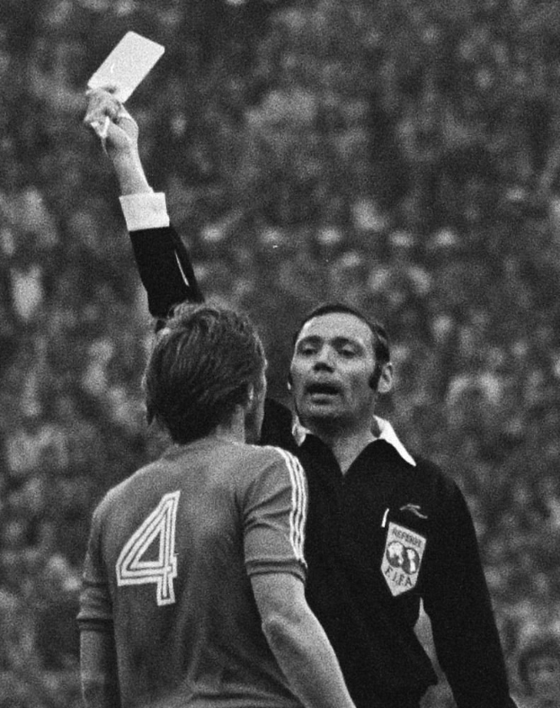Ein Schiedsrichter in Schwarz-Weiß-Fotografie hält eine gelbe Karte hoch