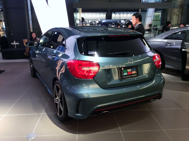 Ein Mercedes-Benz A-Klasse Hatchback auf der IAA in Frankfurt, ein schlankes, modernes Design mit glänzender schwarzer Lackierung, Chromakzente, sportliches Aussehen, niedriger Profil, breite Basis, markantes Grill und Aluminiumräder, umgeben von einer Gruppe von Menschen.