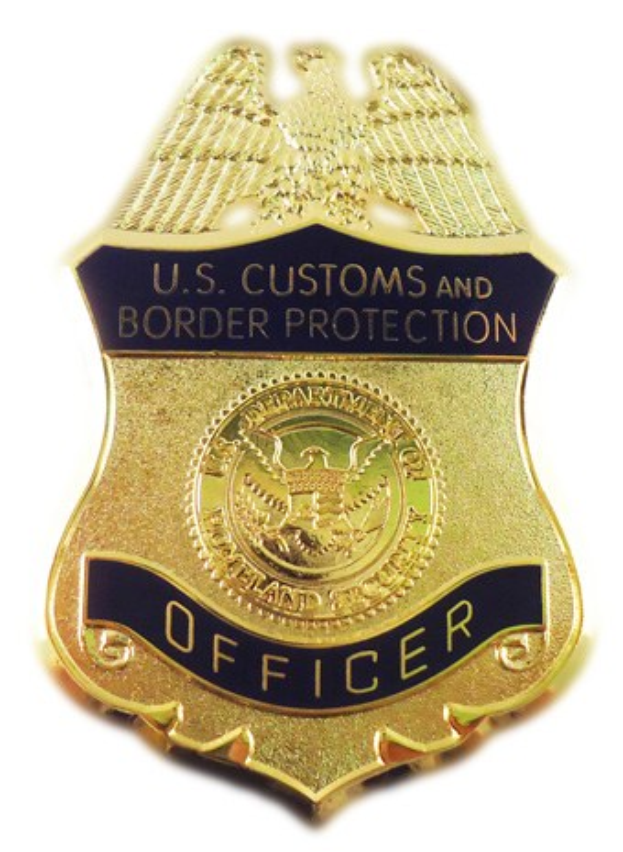 Goldabzeichen mit der Aufschrift "U.S. Customs and Border Protection Officer" vor einem weißen Hintergrund.