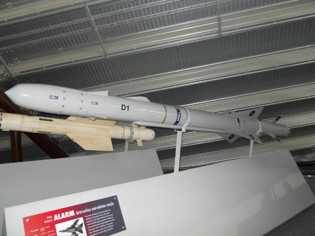 Raketen werden mit einer weißen Tafel am Boden gezeigt, die ein rotes und graues Plakat mit Text auf der linken Seite und ein weißes Dach oben aufweist.