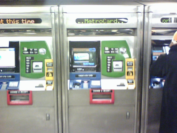 Automatische Fahrkarten-Automaten mit einer Person rechts daneben.