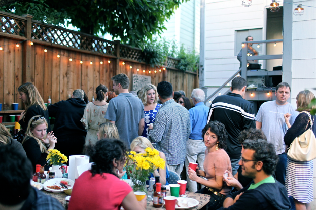 Eine Gruppe von Menschen auf einer Party, einige sitzen an einem Tisch und andere stehen.