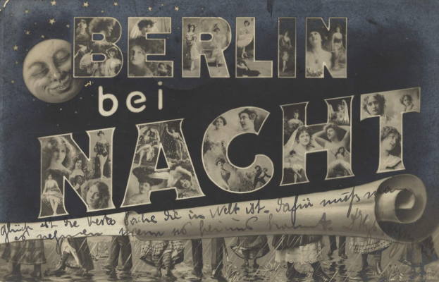 Schwarzes und weißes Foto einer Gruppe von Menschen, die vor einem "Berlin Bei Nacht"-Schild mit einem Mond im Hintergrund lachen und strahlen, das Schild mit Sternen und Streifen geschmückt.