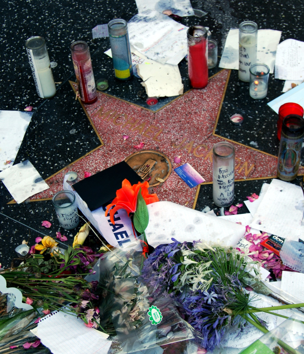 Star auf dem Hollywood Walk of Fame mit Blumenbouquets, Kerzen, Papieren und anderen Gegenständen drumherum.