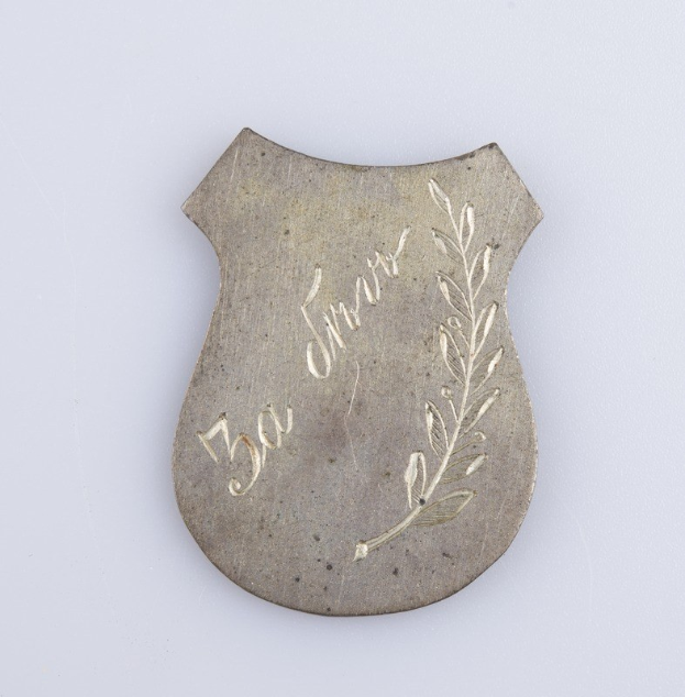 Ein silbergerändertes Abzeichen mit einem Lorbeerkranz, darauf die Inschrift "50. Hochzeitstag", auf einem weißen Hintergrund.