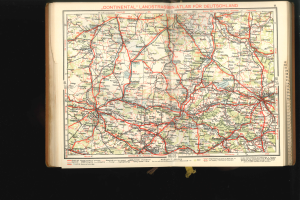 Ein aufgeschlagenes Buch, das eine detaillierte Karte von Deutschland mit Straßen und Autobahnen zeigt, vor einem schwarzen Hintergrund.