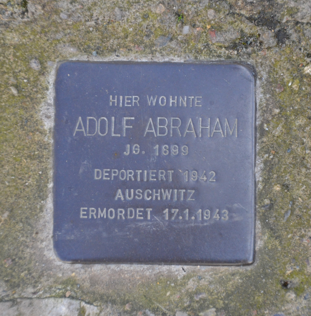 Plakette an einer Steinwand mit der eingravierten Inschrift "Adolf Abraham".