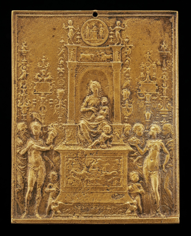 Goldene Plakette mit detaillierter Skulptur einer Frau in einem langen Kleid und einem Mann in einem Anzug, gerahmt in Gold, vor schwarzem Hintergrund.