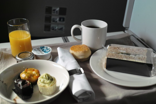 Ein Tischgedeck mit Tellern, Lebensmitteln, einem Becher, einem Glas und einem Tuch.