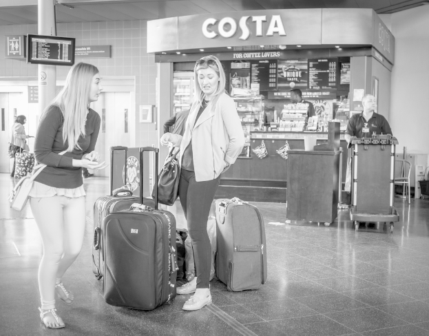 Zwei Frauen mit Gepäck vor einem Café in einem Flughafen