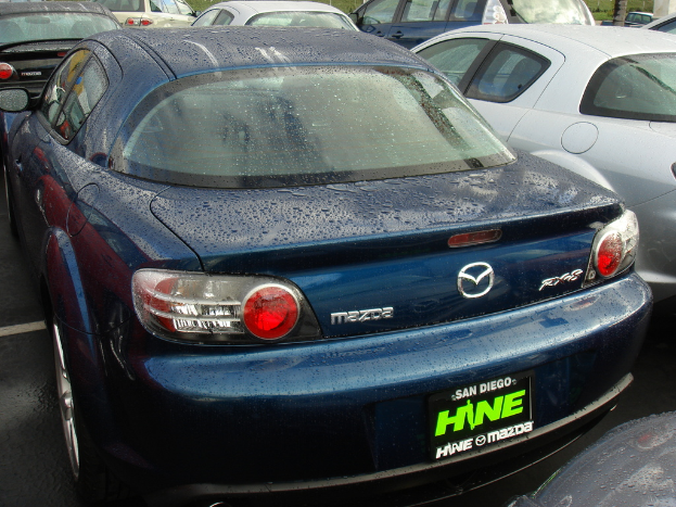 Mehrere Autos stehen auf einem Parkplatz mit einer Tafel, auf der unten Text zu sehen ist.