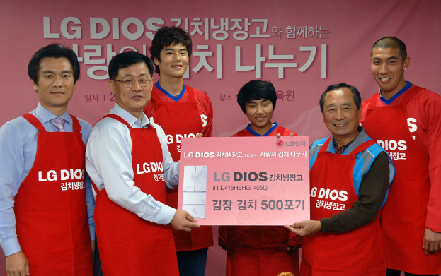 Eine Gruppe von Männern hält eine große Karte der LG-Firma mit einem Banner im Hintergrund.