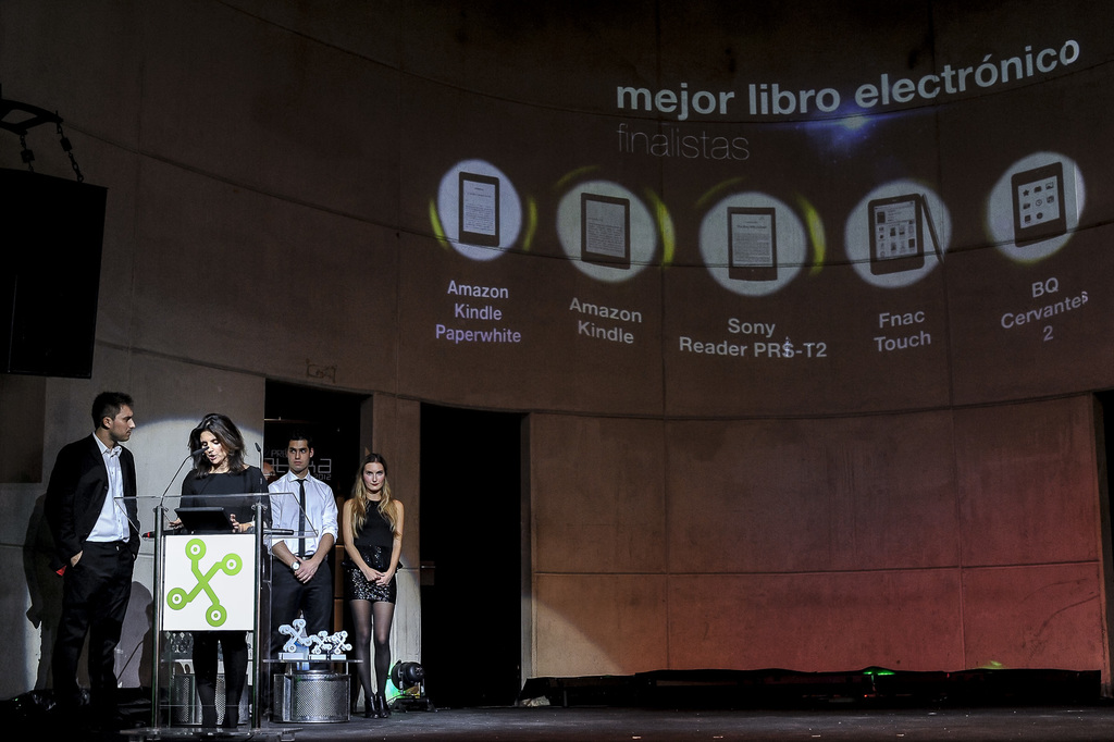 Vier Personen stehen links, wobei eine Frau ein Seminar hält; im Hintergrund sind Bilder von Gadgets zusammen mit ihren Namen dargestellt.