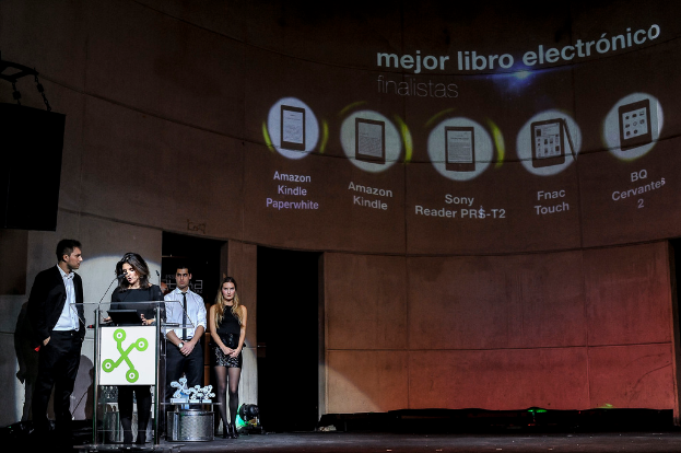 Vier Personen stehen links, wobei eine Frau ein Seminar hält; im Hintergrund sind Bilder von Gadgets zusammen mit ihren Namen dargestellt.