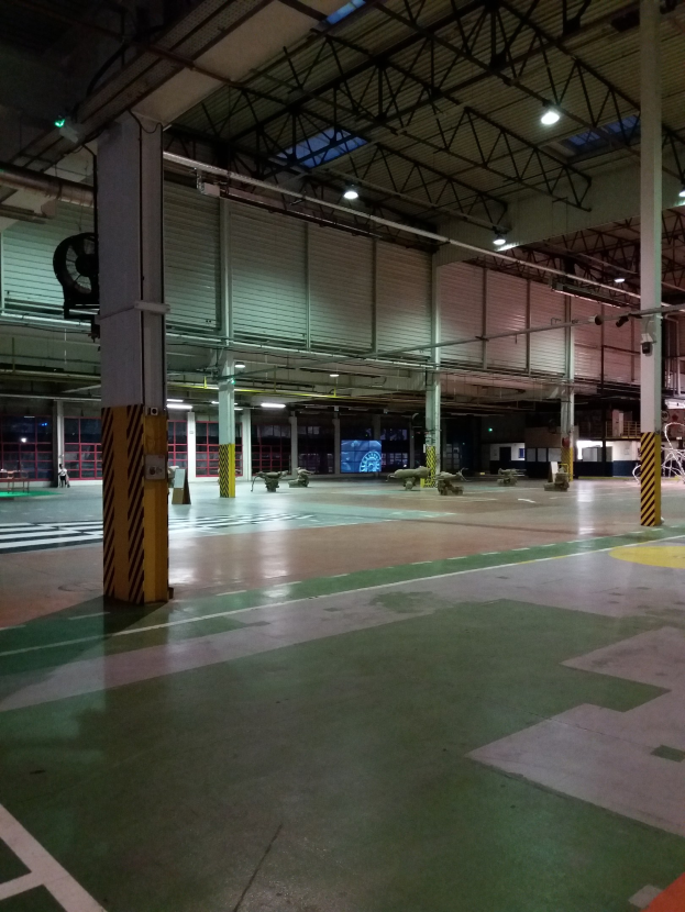 Ein großes Lager voller verschiedener Maschinen, Metallstangen, Lampen und anderer Gegenstände, mit Text auf dem Boden auf der rechten Seite.