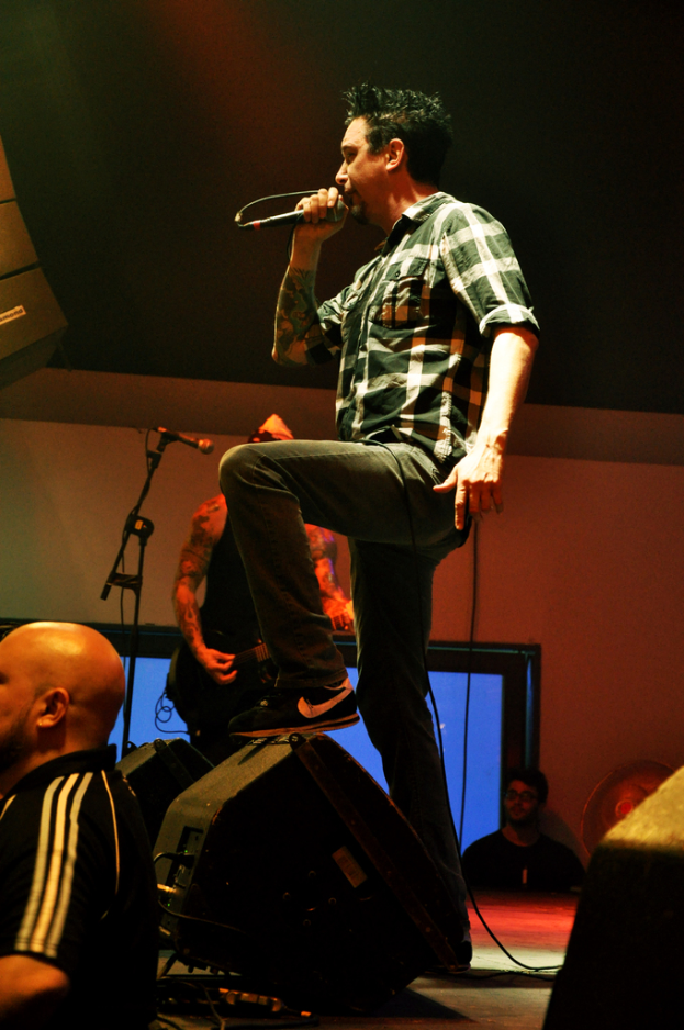 Eine Person auf der Bühne mit einem Mikrofon singend, mit einer anderen Person links auf dem Boden stehend.