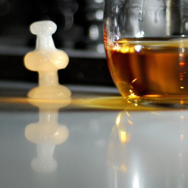 Ein Weinglas und ein weißer Schachstein sind auf einem Tischdeckel platziert.