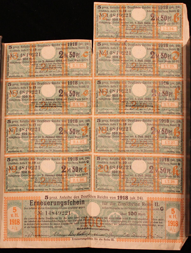 Ein altes Buch mit einem Stapel deutscher Reichsbanknoten von 1918, Nennwerte sichtbar, auf einem schwarzen Hintergrund.