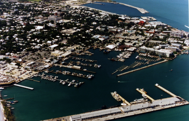 Eine Vogelperspektive einer Stadt mit zahlreichen Gebäuden, Meerwasser und einem Hafen an der vorderen Unterseite, mit mehreren Schiffen.
