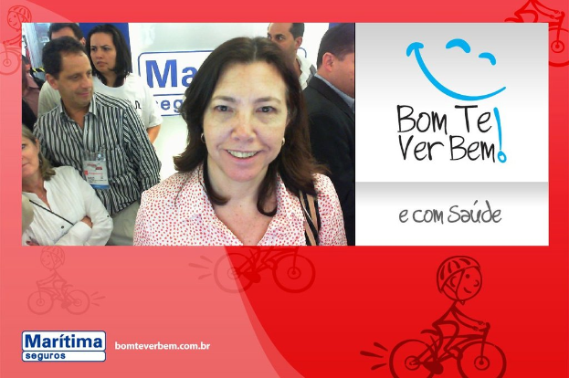 Eine Frau steht lächelnd im Vordergrund, mit Menschen im Hintergrund, Text und ein Cartoon-Emoji oben rechts und eine Cartoon-Person, die unten fährt.