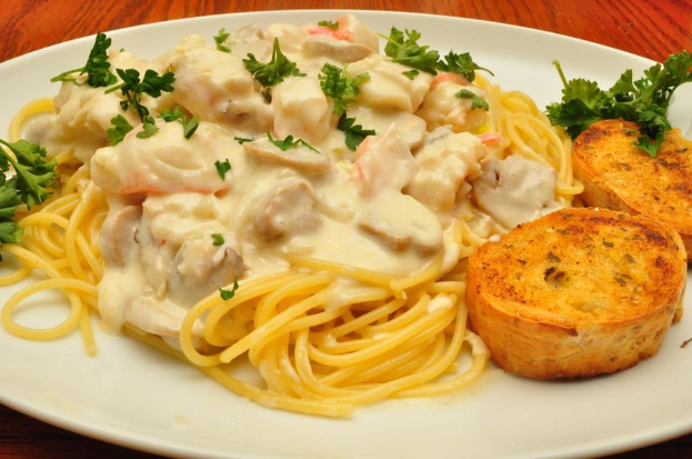 Ein Teller auf einer hölzernen Oberfläche mit Nudeln, Blättern und anderen Speisen.