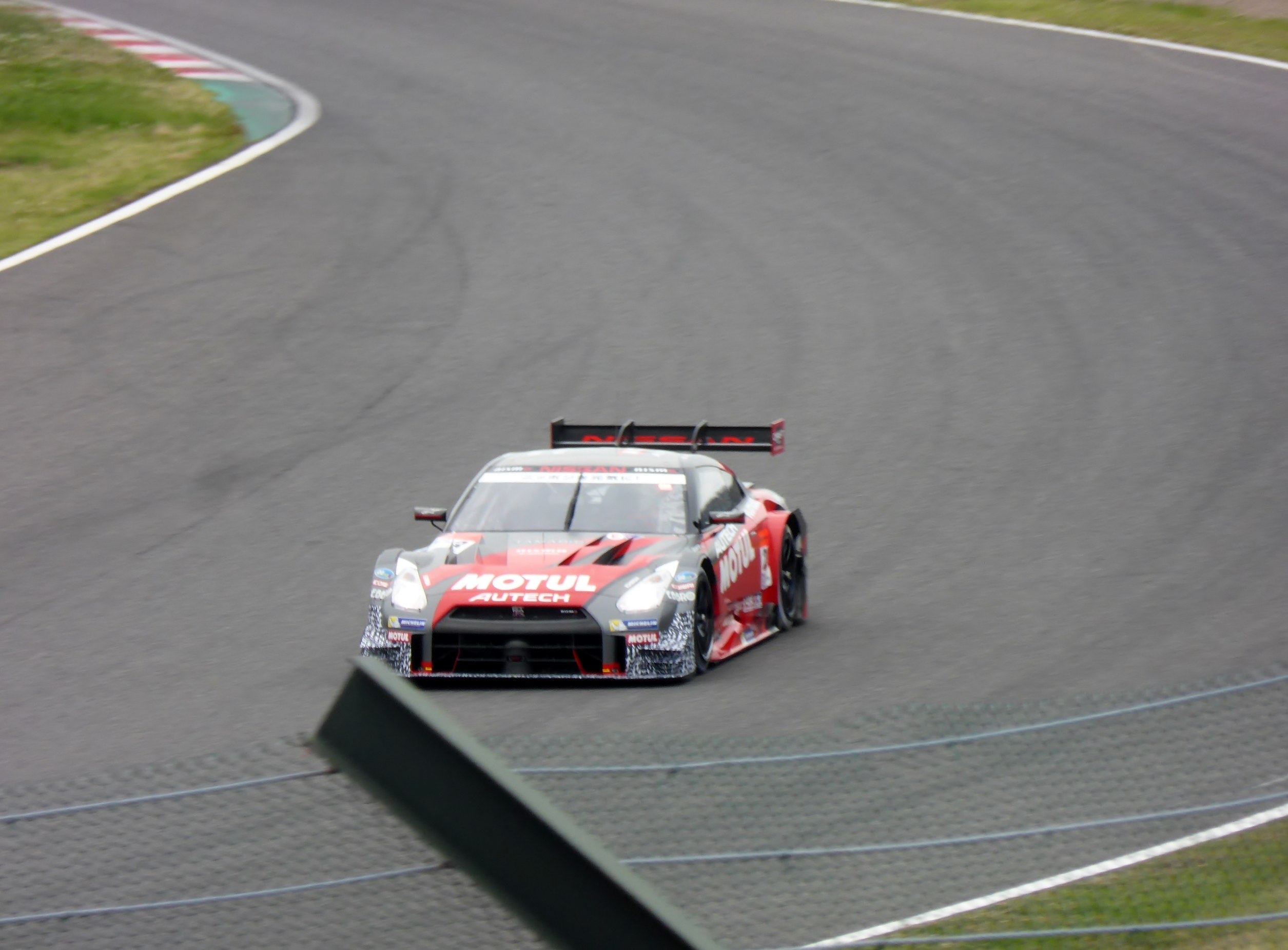 Ein Nissan GT-R Nismo GT3-Rennwagen auf der Nürburgring 24 Stunden-Strecke, mit grünem Gras auf beiden Seiten der Strecke.