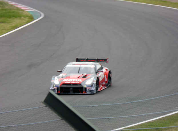 Ein Nissan GT-R Nismo GT3-Rennwagen auf der Nürburgring 24 Stunden-Strecke, mit grünem Gras auf beiden Seiten der Strecke.