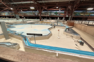 Indoor-Wasserpark mit mehreren Rutschen, Deckenleuchten, Wandgemälden und einem Minigolfplatz.