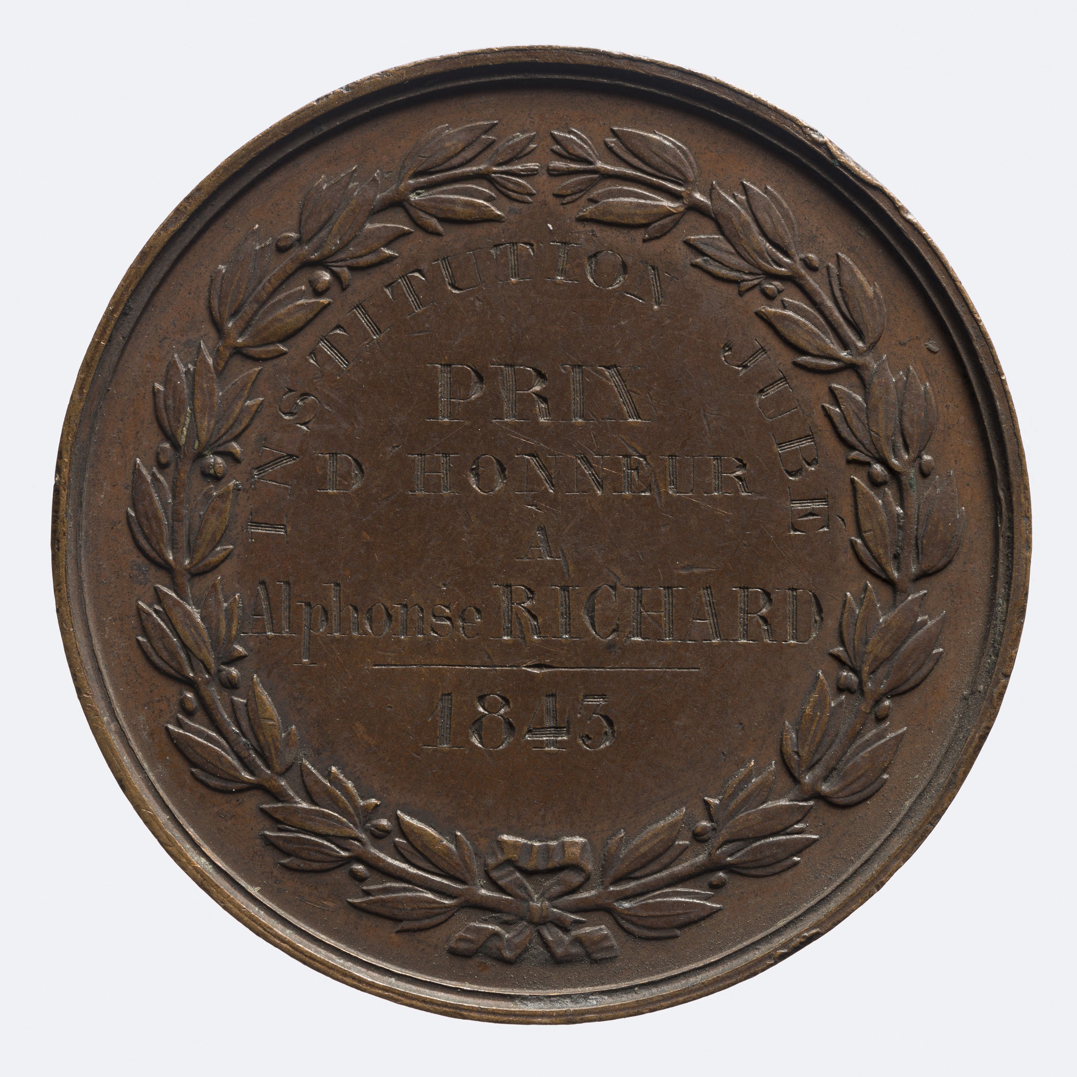 Bronze-Medaille mit Lorbeerkranz-Design, mit eingravierter Beschriftung, vor einem weißen Hintergrund.