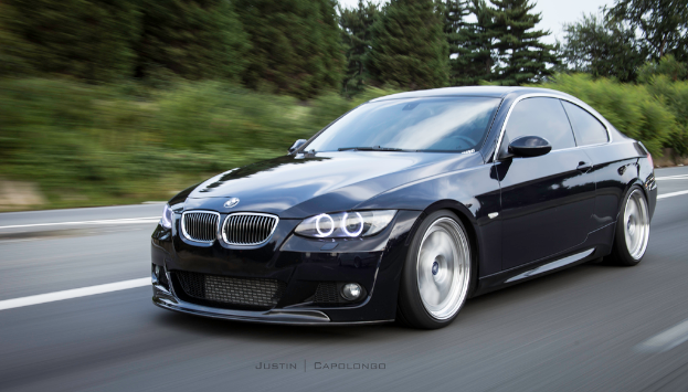 Ein schwarzer BMW auf einer StraÃŸe mit BÃ¤umen im Hintergrund.
