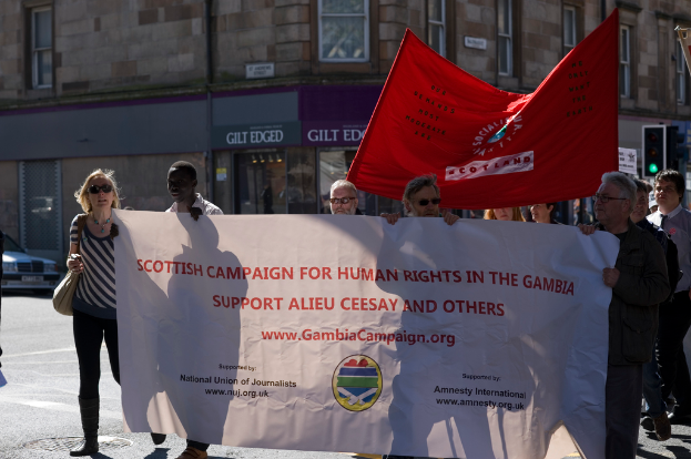 Ein Gebäude mit Fahnen, einer Ampel und einigen verstreuten Menschen.