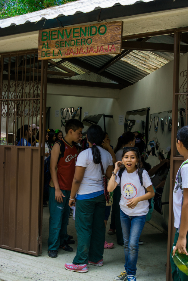 Ein Geschäft mit einem Eisenblechdach und einer Schildertafel mit Text oben drauf, mit Menschen drinnen.